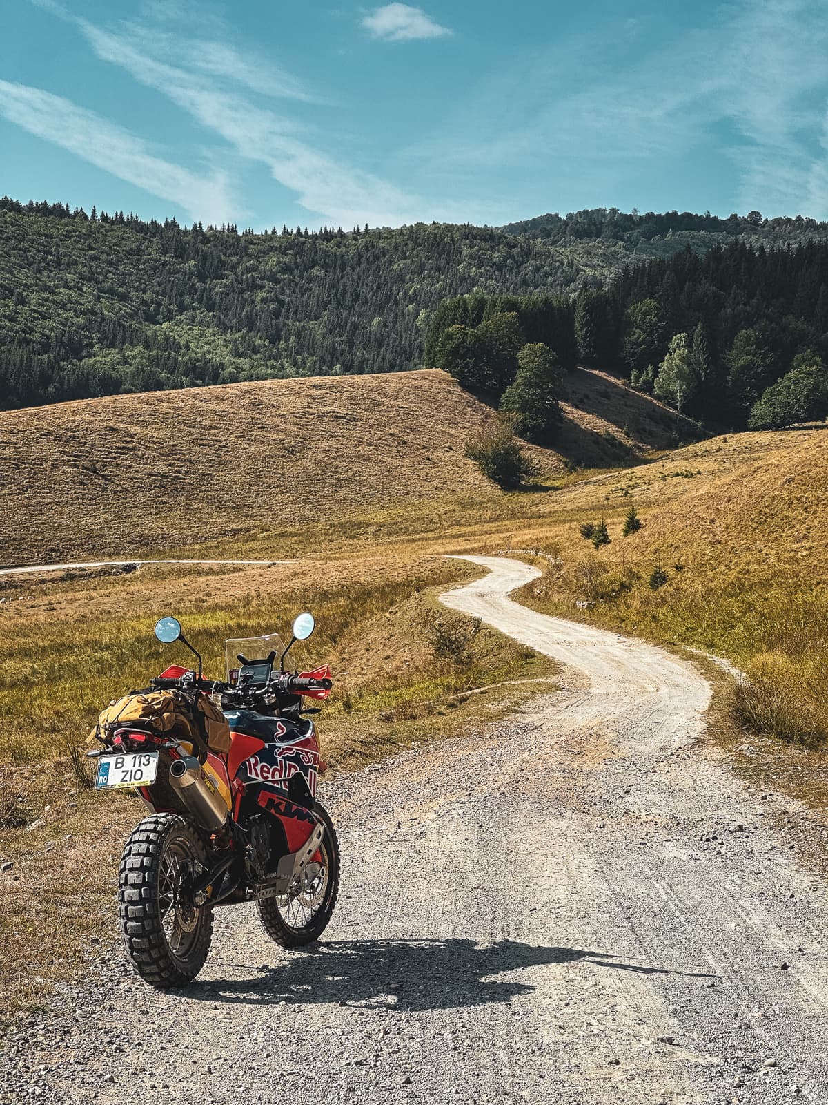 Loaded adventure motorcycle on winding gravel through the hills