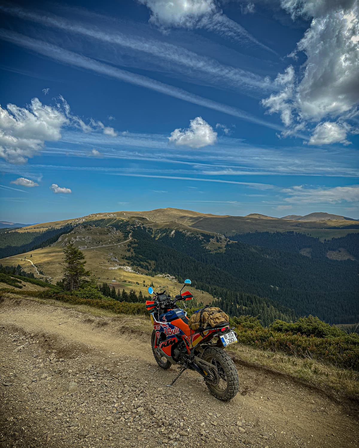 Loaded adventure motorcycle at the top of the ridge with mountain ranges to the horizon
