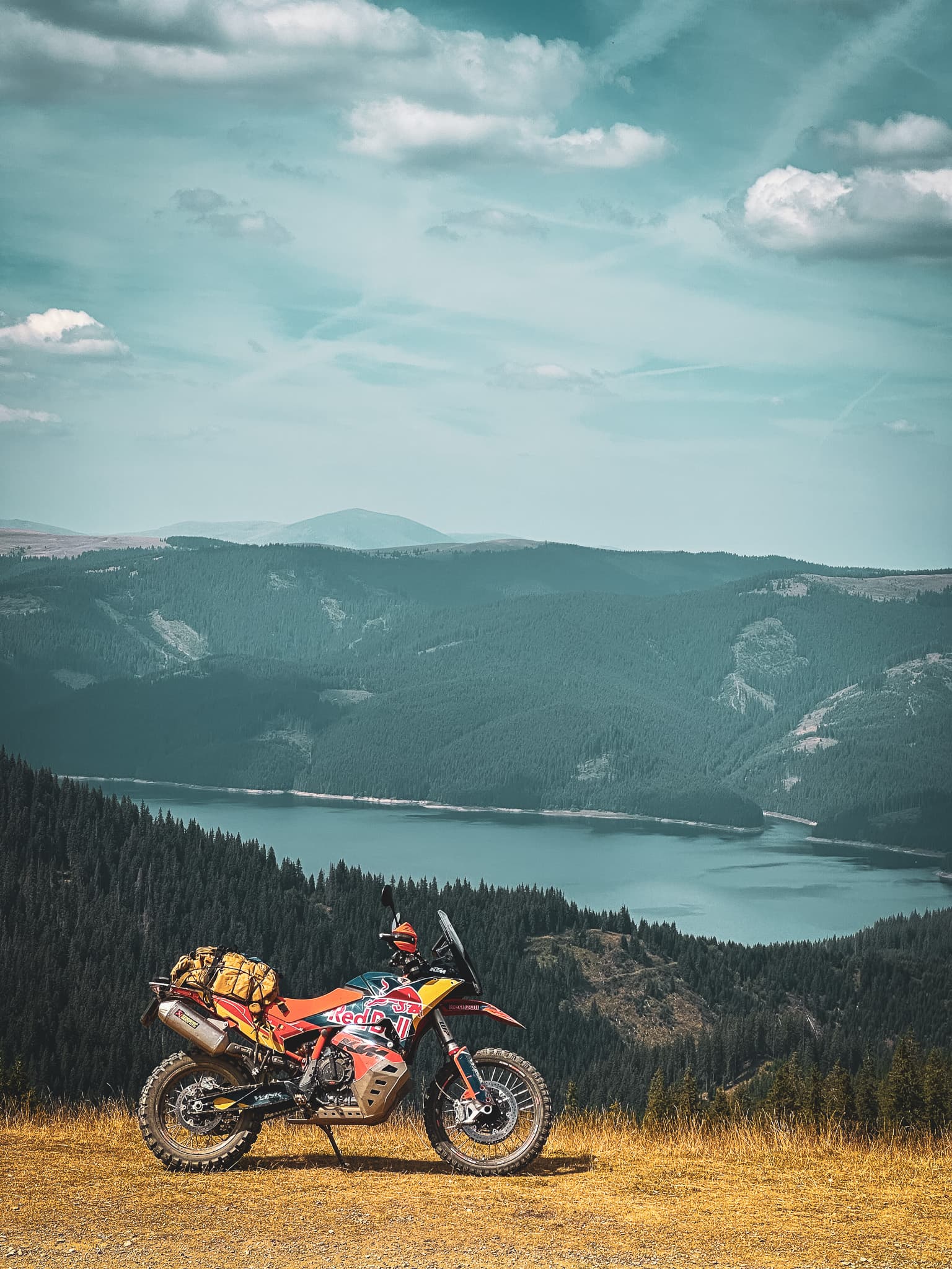 Loaded KTM adventure motorcycle on a ridge above a mountain lake in the Carpathians